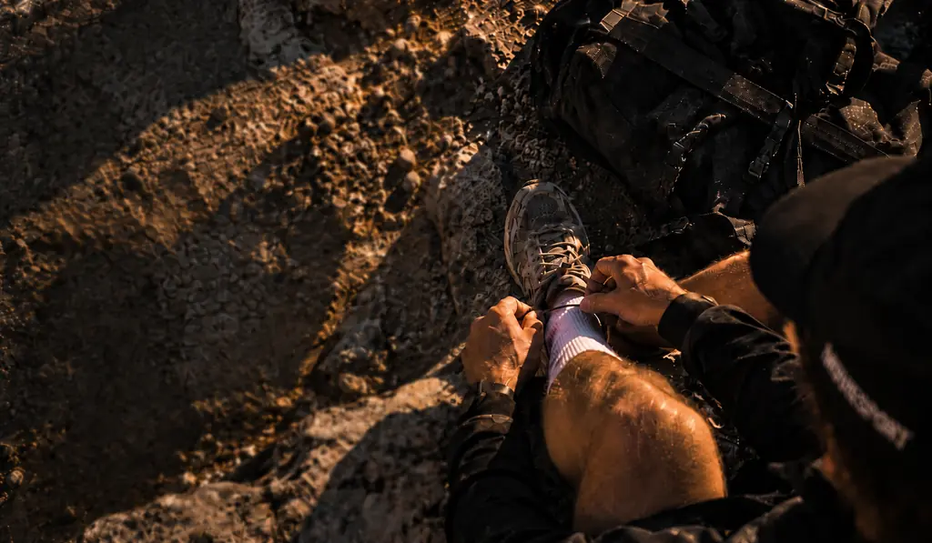 Mains qui lacent une chaussure de trail avant l’effort, lumière rasante